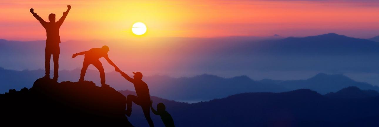 People climbing a mountain at sunset